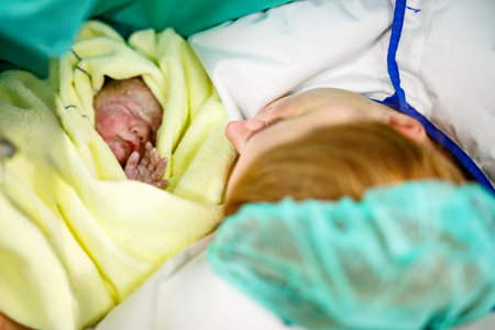 Newborn baby wrapped in blankets after birth. Mother looking for the first time on new born daughter. Newborn child seconds and minutes after birth. Happy mum cryingの写真素材