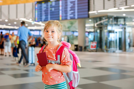 Little preschool girl at airport terminal. Happy child going on vacations by airplane. Smiling kid with passport and bag.の写真素材