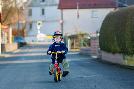 Little boy riding bicycle in village or city. Happy preschool child on balance bike, having fun. Outdoor leisure and games for children.の写真素材