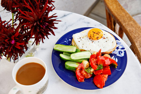 Healthy breakfast with fried egg, cucumber, fresh tomatoes and herbs. Nutritious morning meal with...