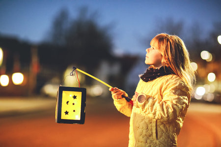 Little preschool kid girl holding selfmade traditional lanterns with candle for St. Martin...