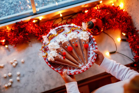 Close-up of little girl holding reindeer made with chocolate cocoa powder and marshmallows. Selfmade dessert drink for children on Christmas. Closeup of hands of childの写真素材