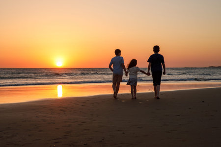 Three kids silhouettes running and jumping on beach at sunset. happy family, two school boys and one...
