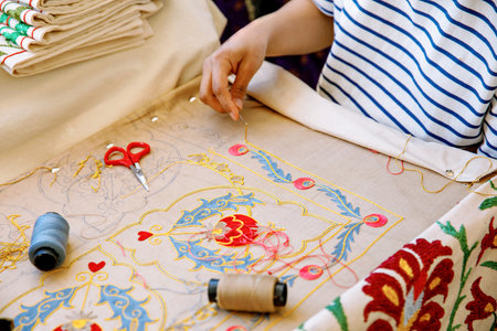 In Tashkent, Uzbekistan, an artisan carefully hand-embroiders a vibrant floral pattern, surrounded...