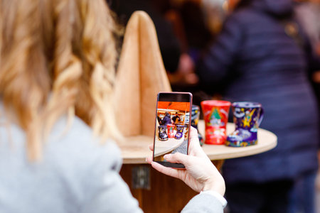 Beautiful young woman drinking hot punch and mulled wine at a German Christmas market, capturing...