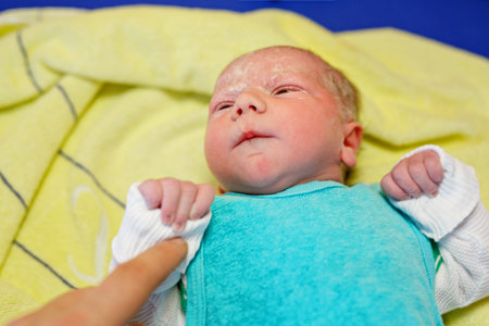 Newborn child crying seconds and minutes after birth. Cute tiny new born baby girl on towel. New...