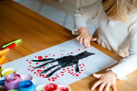 Little preschool girl painting with fingers tree on paper at home or at kindergarten daycare. Child doing creative art activity indoors. Real life, real peopleの写真素材