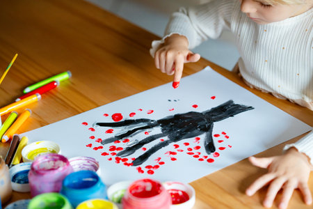 Little preschool girl painting with fingers tree on paper at home or at kindergarden daycare. Child doing creative art activity indoors. Real life, real people.の写真素材