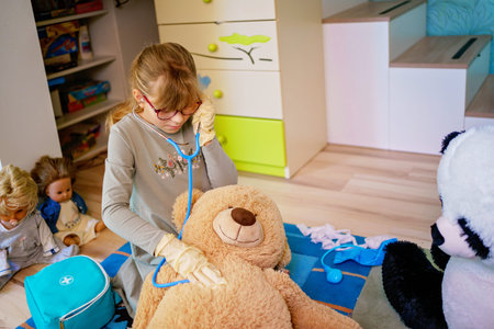 Little girl playing doctor role game with her plush toys at home
