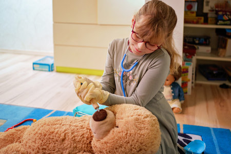 Little girl playing doctor role game with her plush toys at homeの写真素材