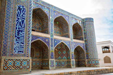 Ulugh Beg Madrasa in Bukhara, Uzbekistan, with richly decorated blue tile arches and geometric...
