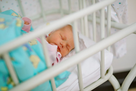 Sleeping newborn baby in bed of maternity birth clinic hospital. Beautiful portrait of little child...