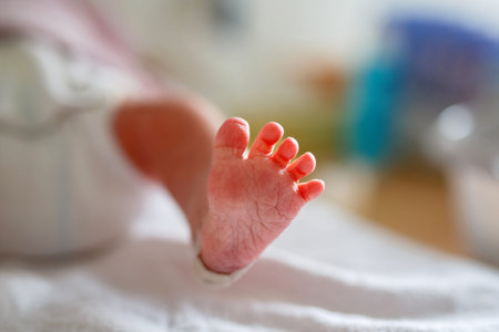 Feet of Newborn child seconds and minutes after birth. Cute tiny new born baby girl or boy on towel....