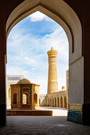 View of the Poi Kalyan complex in Bukhara, Uzbekistan, with Kalyan Minaret framed by an arched portal in historic Islamic architecture.の写真素材