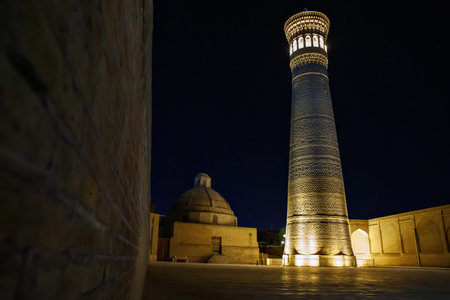 Illuminated Kalon Minaret at night in Bukhara, Uzbekistan, with visitors in the Po-i-Kalyan complex, showcasing Islamic architecture and history.の写真素材