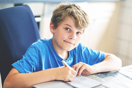 Young boy doing his homework at home. School kid learning