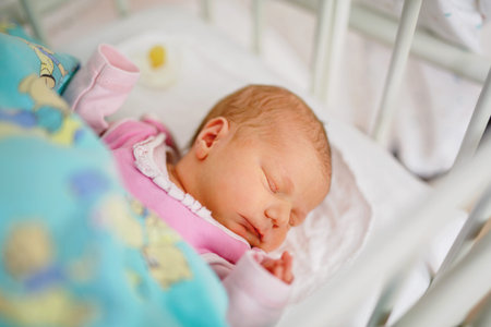 Sleeping newborn baby in bed of maternity birth clinic hospital. Beautiful portrait of little child...