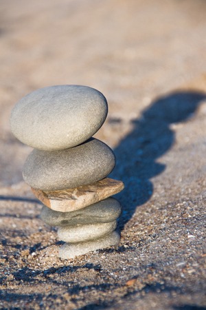 A turret of stones on the sand with a long shadow.の写真素材