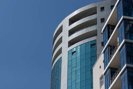 Upper part of the facade of a modern urban building against a blue sky.の写真素材