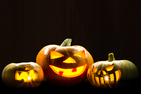Three brightly glowing pumpkins on a dark background. Picture for decoration on the holiday of Halloween.の写真素材