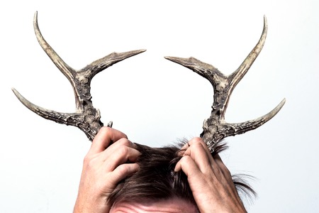 A cheating wife. Her husband has grown horns. Concept on a white background.の写真素材