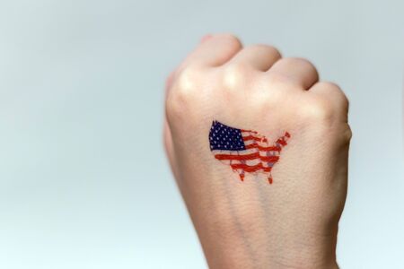 A human fist with images of the symbols of the flag and the territory of the United States.の写真素材