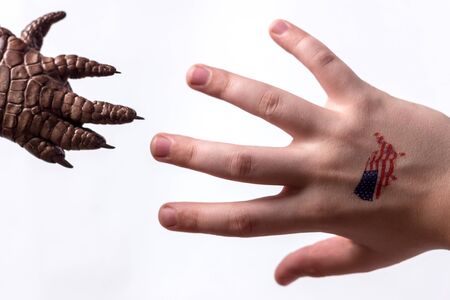 The hand of the guy with his fingers spread out with a sticker of the American flag stretches towards the paw of the monster.の写真素材