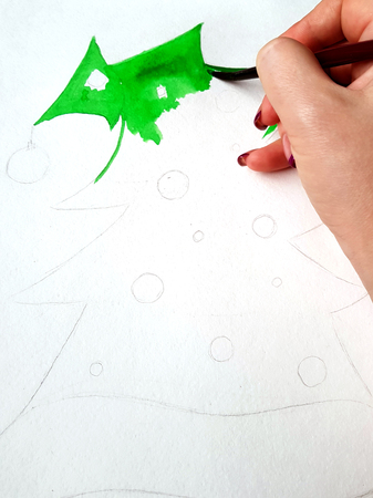 The girl began to paint a new-year decorated Christmas tree with watercolor. Paint texture.の写真素材