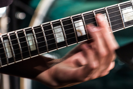 The musician's hand is blurred in motion on the fretboard on the strings of an electric guitar.の写真素材