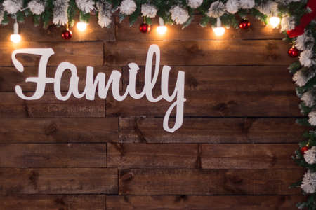 Texture wooden background with white inscription Family decorated with Christmas lights and red ballsの写真素材