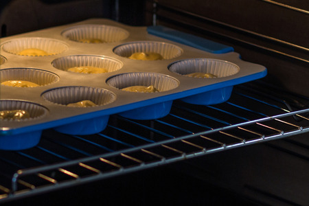 Blue molds with a dough for cupcakes in the oven.の写真素材
