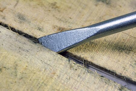 The tip of the mounting tool is inserted into the slot between the wooden boards. The concept of opening the box. Close-up.の写真素材