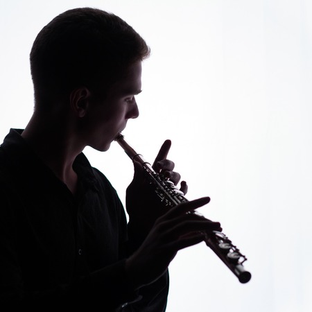 A young man is playing the flute. Silhouette. A square picture. Copy space.の写真素材