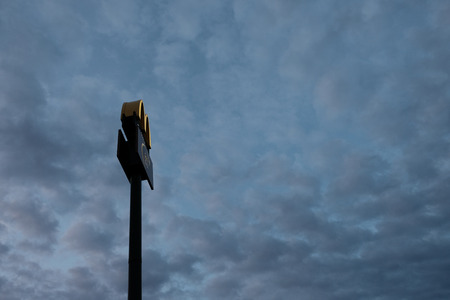 Kostanay, Kazakhstan, Friday July 13, 2018, McDonalds logo on a pillar high in the sky at dawn or dusk. Copy space. Silhouette.のeditorial素材