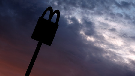 Kostanay, Kazakhstan, July, 2018. Symbol of a round-the-clock power point. The McDonalds logo on the top of the post on the background of sunrise or sunset.のeditorial素材