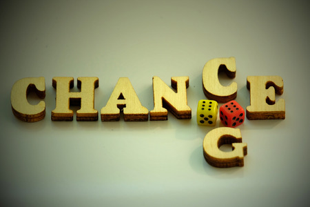 Concept of luck in the game. The word CHANCE, CHANGE from wooden letters and two dice of red and yellow on a white background.の写真素材
