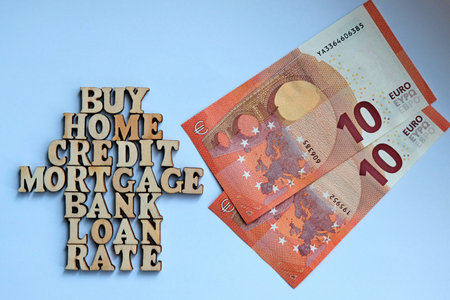 Words on a white background lined in the form of a house of wooden letters next to two bills of 10...