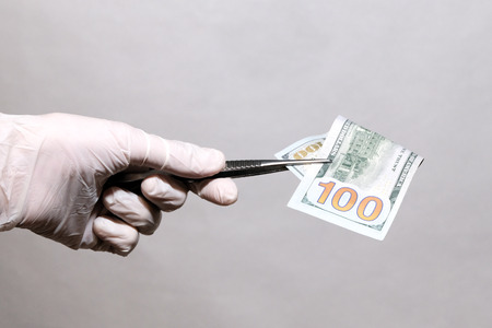 A man holds money in medical gloves. On the white blackground.の写真素材