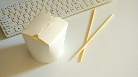 Noodles with crossed sticks behind computer.