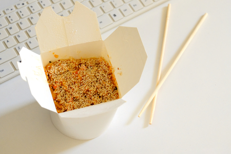 Opened Chinese noodles stand on a white background behind a computer.の写真素材