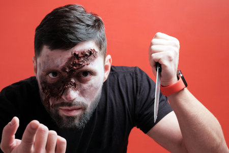 Makeup in the style of Halloween. Close-up. A guy with a terrible wound on half his face with a...