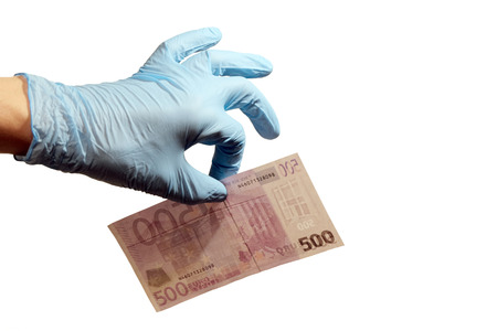 The left hand of a man in a blue rubber glove holds five hundred euros with two fingers. The concept of corruption in medicine, science or forensics. Copy space. Isolated on white background.の写真素材