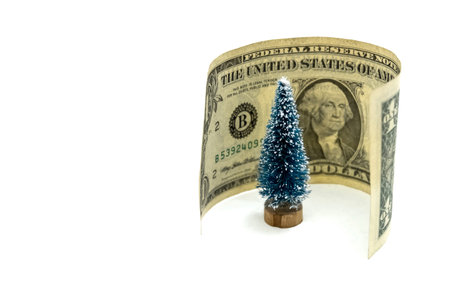 One dollar around the souvenir festive Christmas tree on a white background. Concept of the cost of celebrating the New Year. Face side with a portrait of the president on a small US banknote.の写真素材