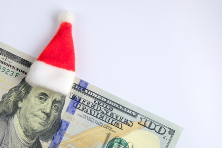 Santa Claus hat on the head of President Franklin. The concept of New Year's holidays and finance. US hundred dollar bill on a white background. Copy space.の写真素材