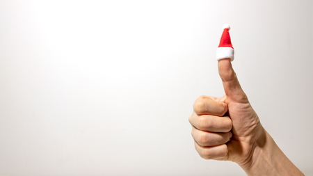 Thumb up on the right hand with a Christmas hat. The concept of a great new year. Light background. Not isolated. Copy space.の写真素材