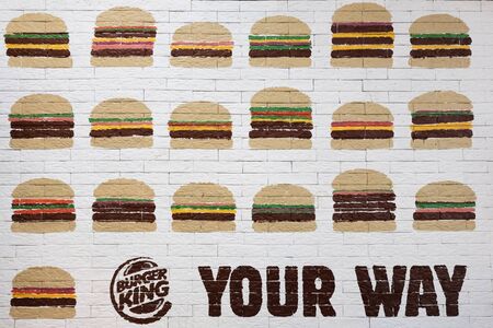 Kostanay, Kazakhstan, 11-25-2018, BURGER KING logo, YOUR WAY inscription and many cheeseburgers or hamburgers painted on white brick wall. Opening day of the popular restaurant. Business item fast food.のeditorial素材