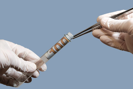 A doctor or a lab technician in white gloves pulls out a hundred dollars from a test tube with tweezers. Concept corruption and analysis, law and forensic investigations. Isolated. Blue background.の写真素材