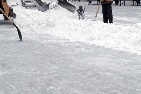 Municipal urban road maintenance.The tractor cleans the street from the snow in the city. Working shovels rake snow. Cleaning after a snow-storm. Copy space.の写真素材