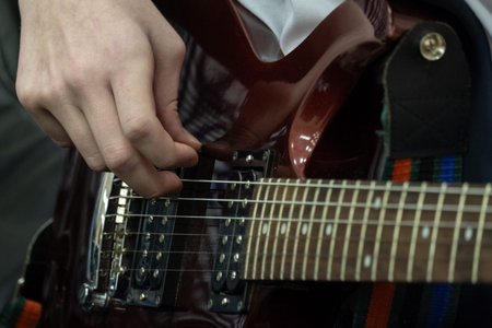 The fingers of a young bassist are pulling bass strings. Teenager plays the electric guitar. Musical...