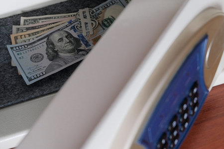 The open door of the safe deposit box. American dollar bills in the safe close-up. Protection against burglary and theft. Storage of jewelry and money in a safe place in the office or at home.の写真素材